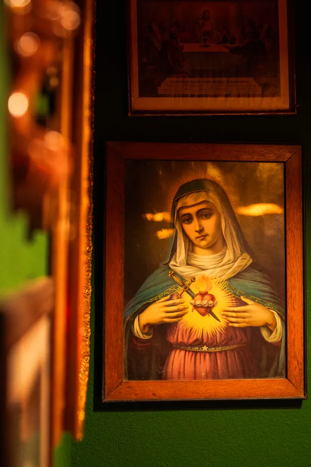 The green-walled nook with a sacred heart painting, warm lamp light, and vintage books